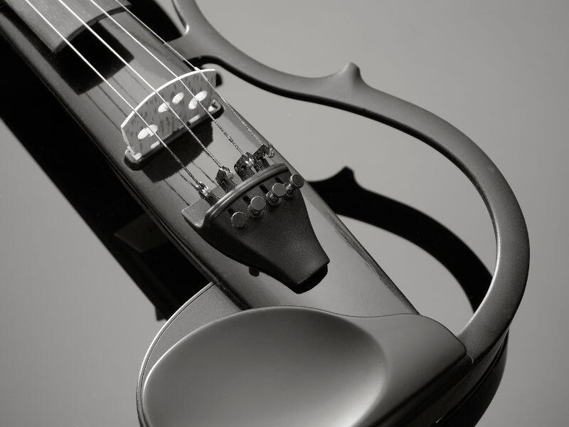 Primer plano de un elegante viol&iacute;n el&eacute;ctrico negro sobre una superficie reflectante. Las cuerdas y el diapas&oacute;n est&aacute;n enfocados, resaltando su dise&ntilde;o moderno y elegante.